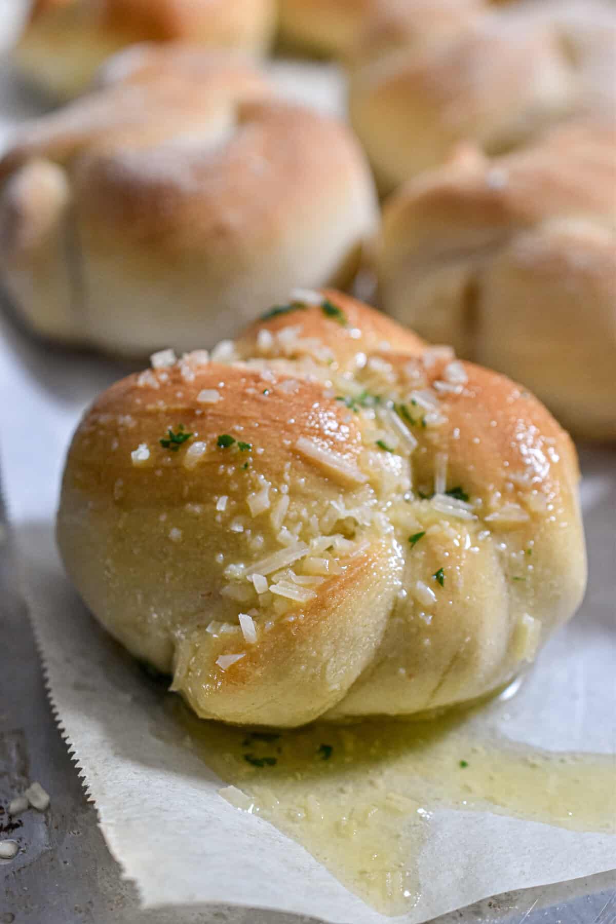 The sourdough discard garlic knot is on a parchment lined baking sheet.