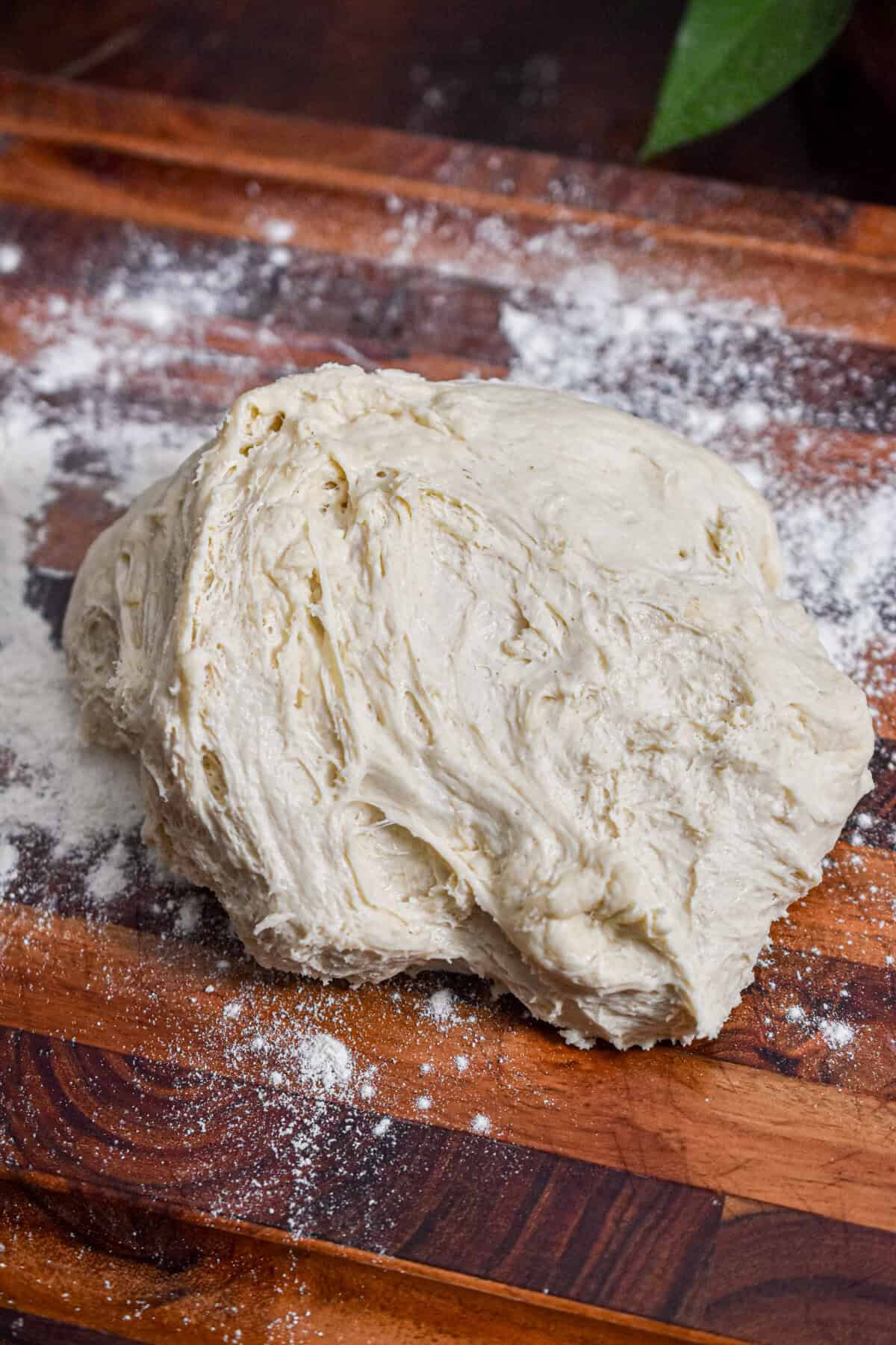 The garlic knot dough is on a wooden cutting board.