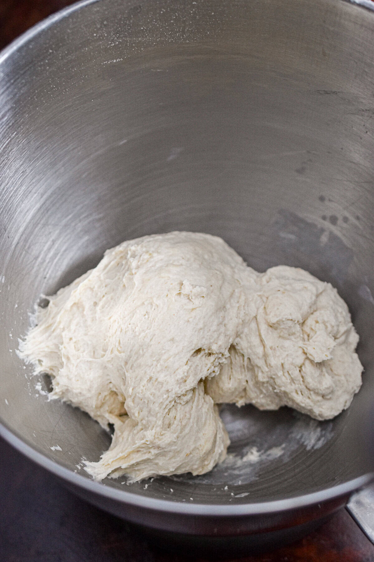 The dough has come together in the bowl of a stand mixer.